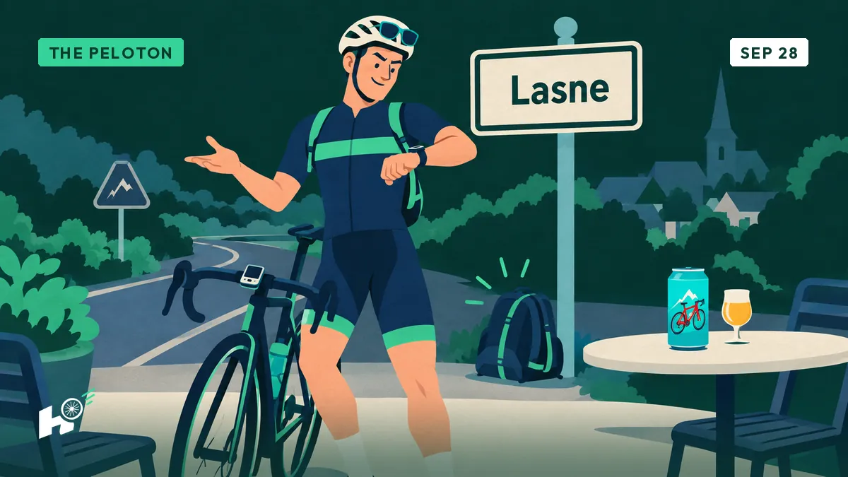 An amateur cyclist raises a toast beside a turquoise can at the Lasne village sign, backpack on the ground.